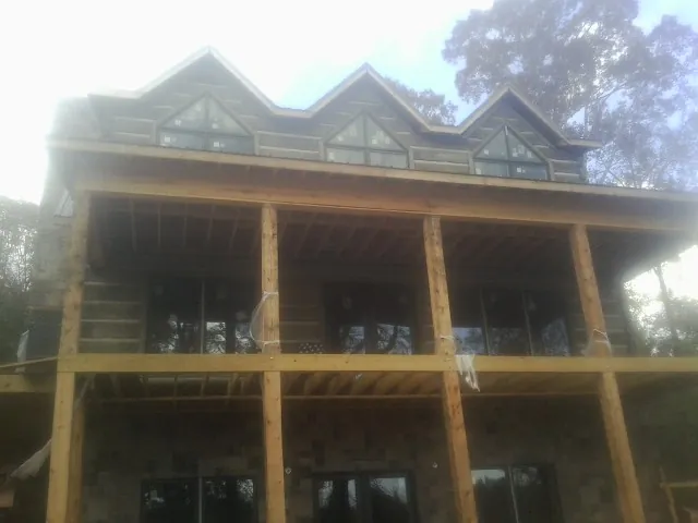 Dormers and porch framing on a large log home under construction — Roof Coating work by our crew in Ontario