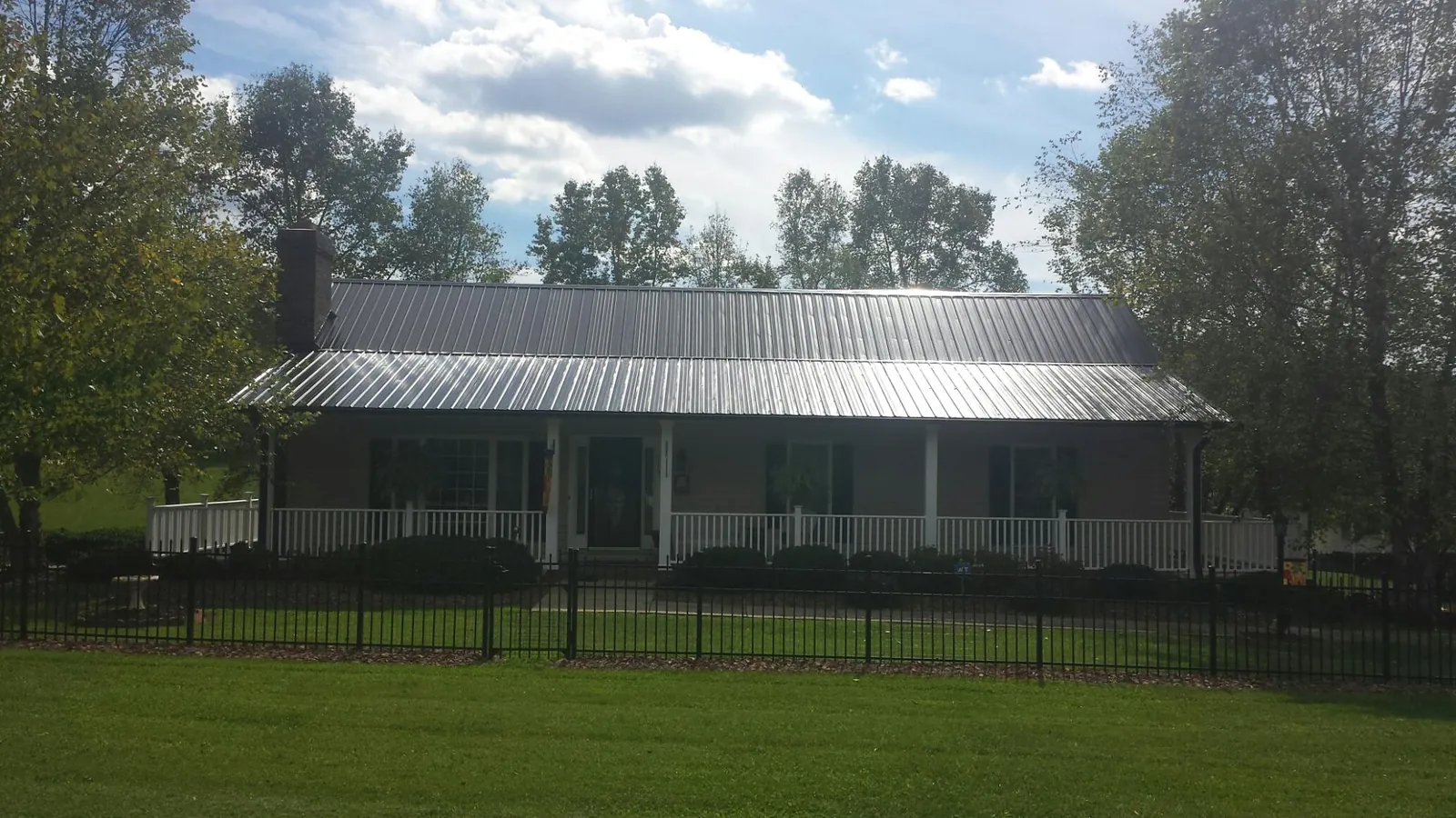 Gray metal roof on a brick ranch with a full width front porch — Gutter Guard Installation work by our crew in Ontario